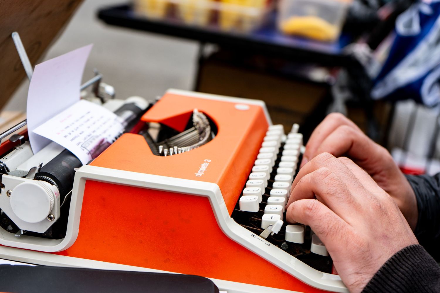 Photo of hands of a poet at work at an orange typewriter