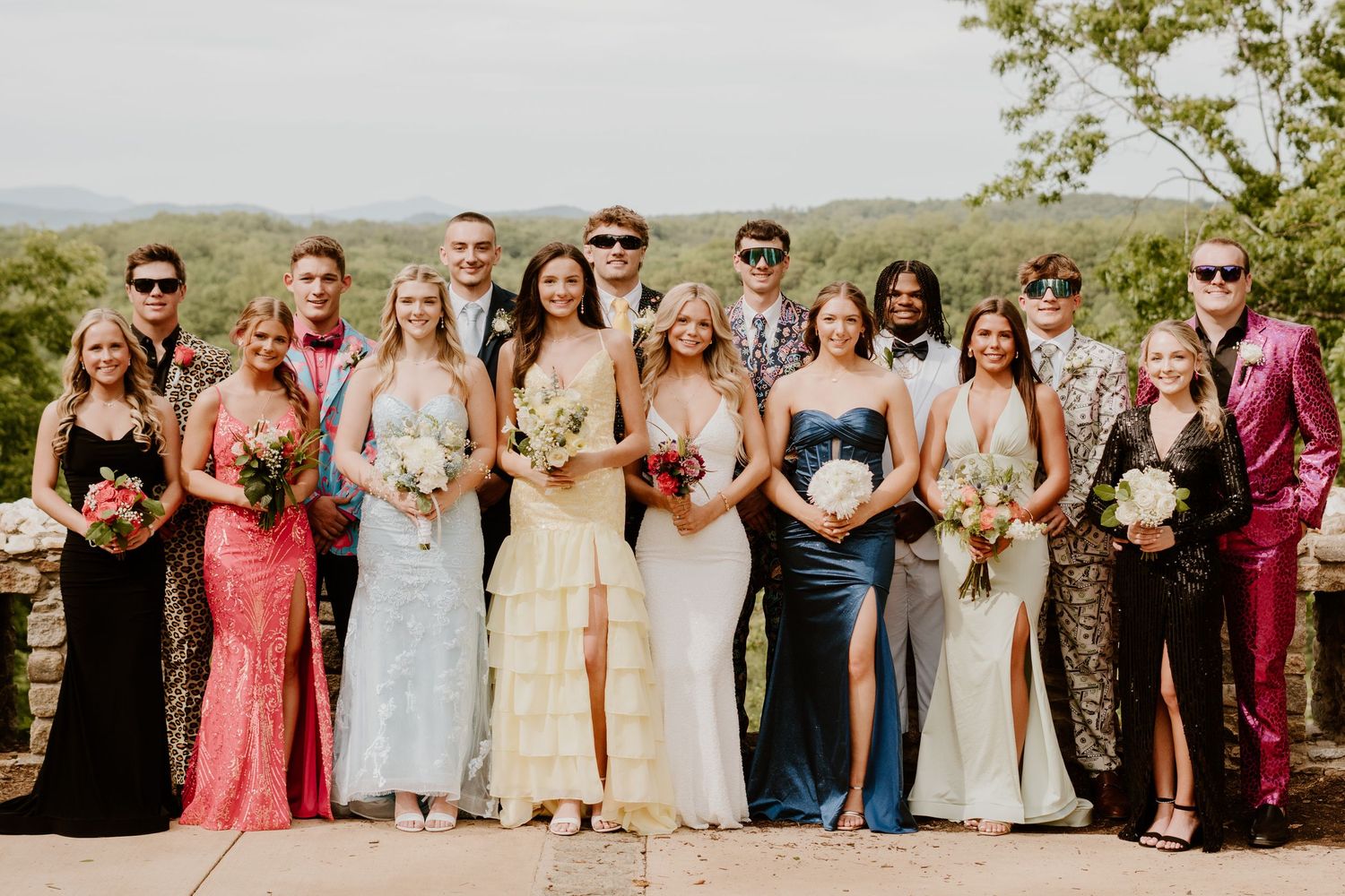 Wedding party members lined up outdoors in colorful formal attire.