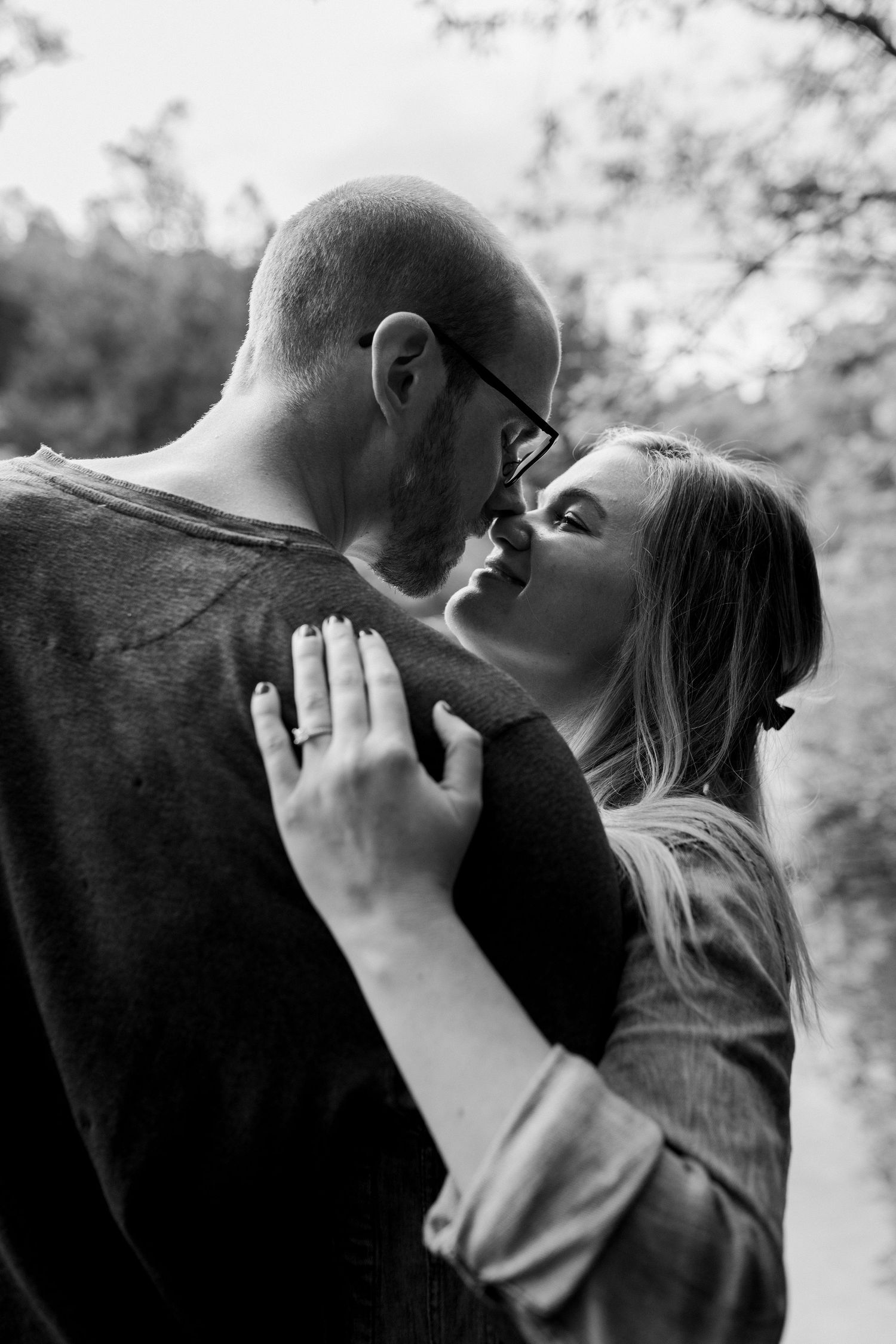 Black and white portrait of couple sharing intimate moments in natural setting.