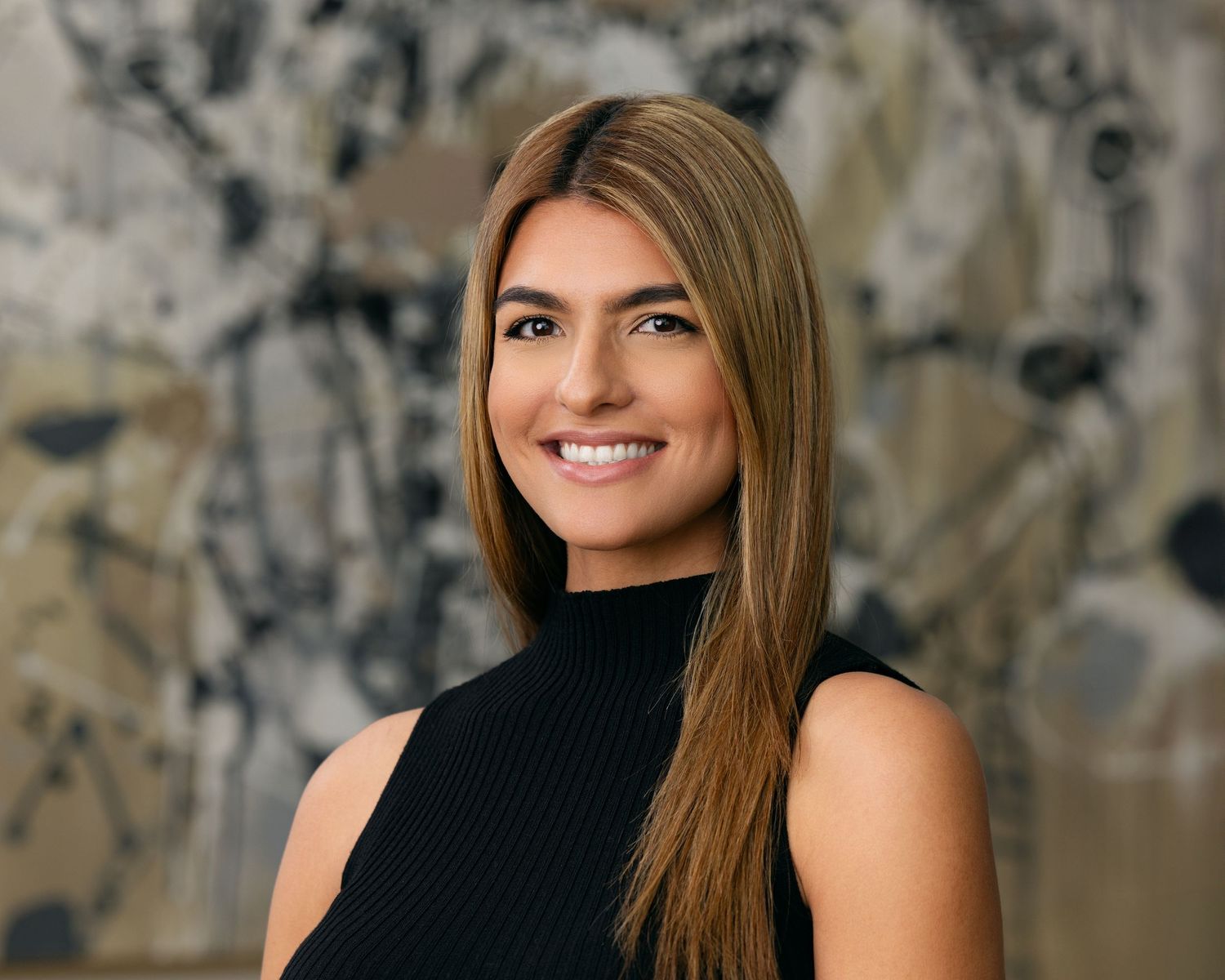 Professional headshot photography of a woman with long brown hair wearing a black sleeveless top, photographed against a modern abstract bac