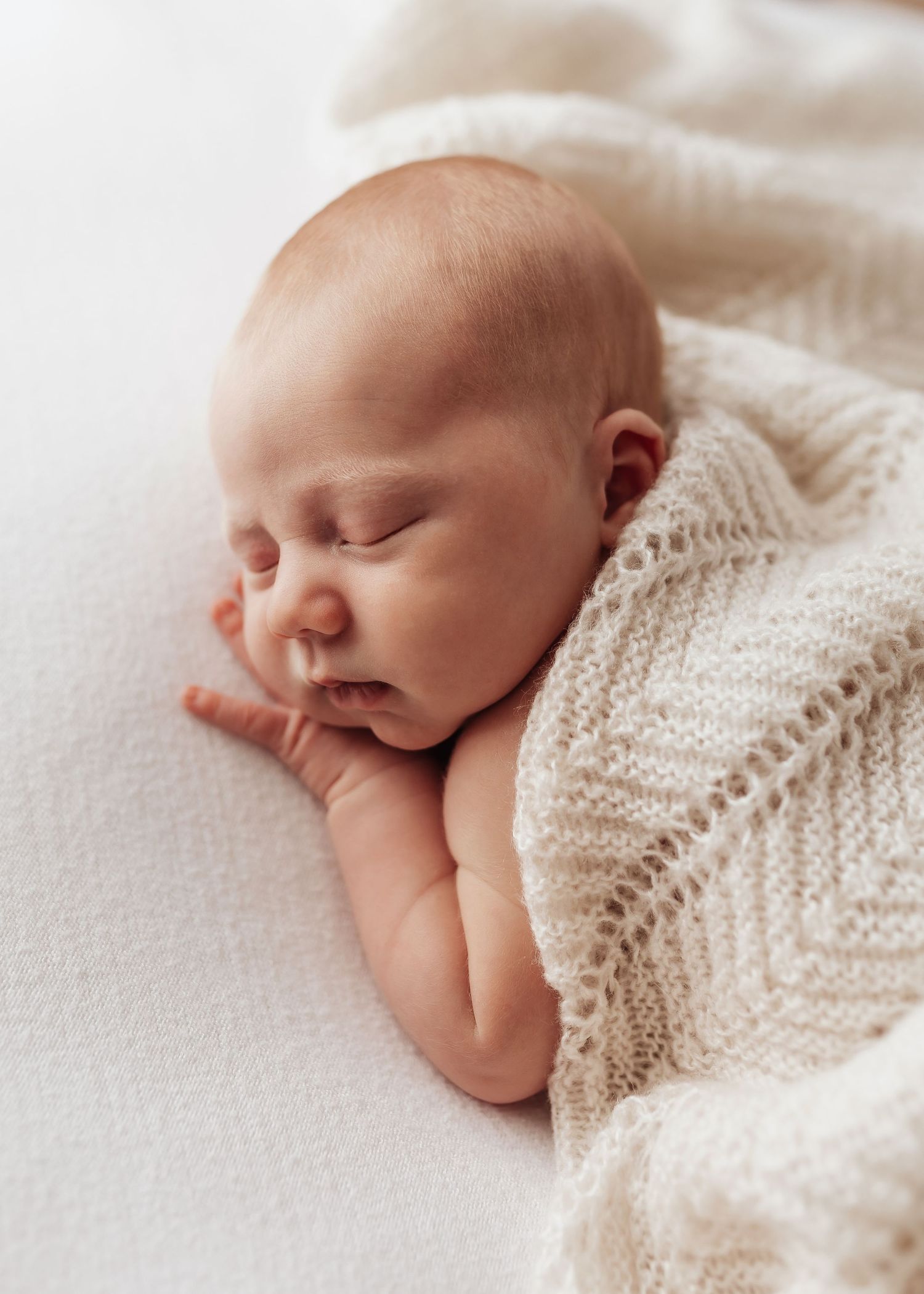 Sweet baby wearing a delicate white lace outfit against light background.