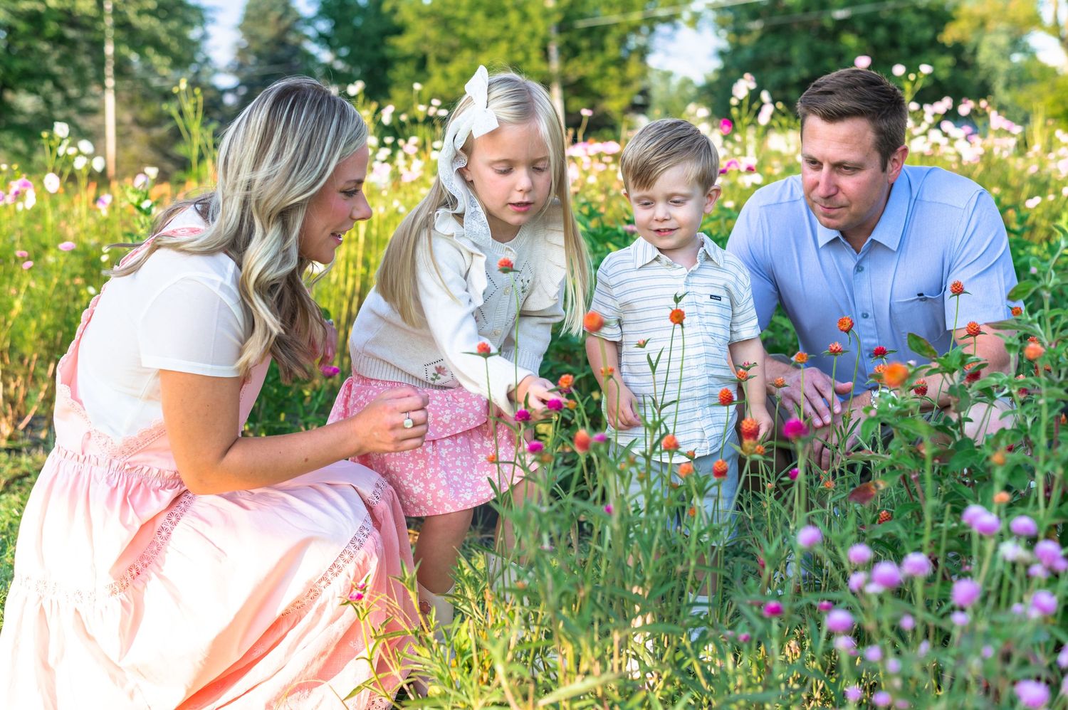 Family gathering in blooming wildflower field during golden hour photography session.