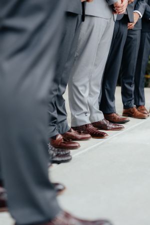 Detail shot of groomsmen's polished brown dress shoes lined up on white floor.