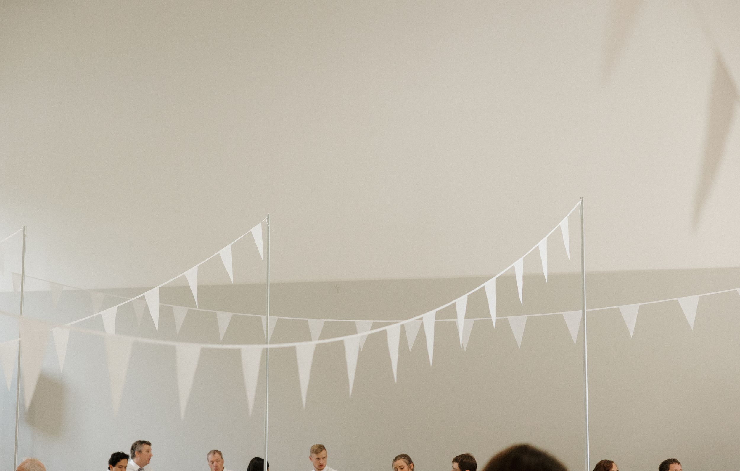 Wedding reception setup with white bunting decorations hanging from the ceiling.