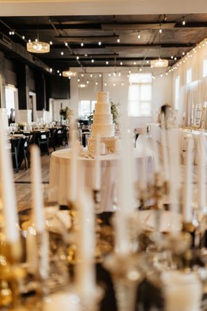 Modern white reception venue with hanging lights and elegant table settings.