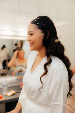 A bridal preparation scene in a bright dressing room with white robes.