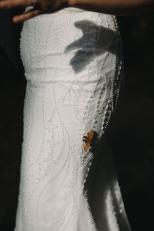 Close-up details of intricate beadwork on a white wedding dress.