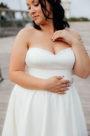 Elegant white wedding dress details shown in cropped portrait style.
