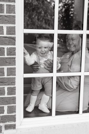 Black and white photo of a joyful scene through a window pane.