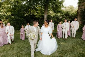 Wedding party in lilac and white attire gathered on green lawn.