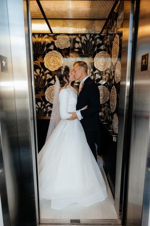 Wedding couple in elevator with decorative floral wall panels.