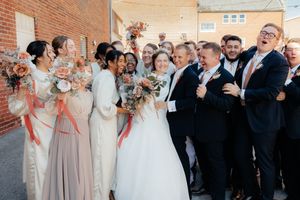 Wedding party celebrating outdoors in front of brick building.