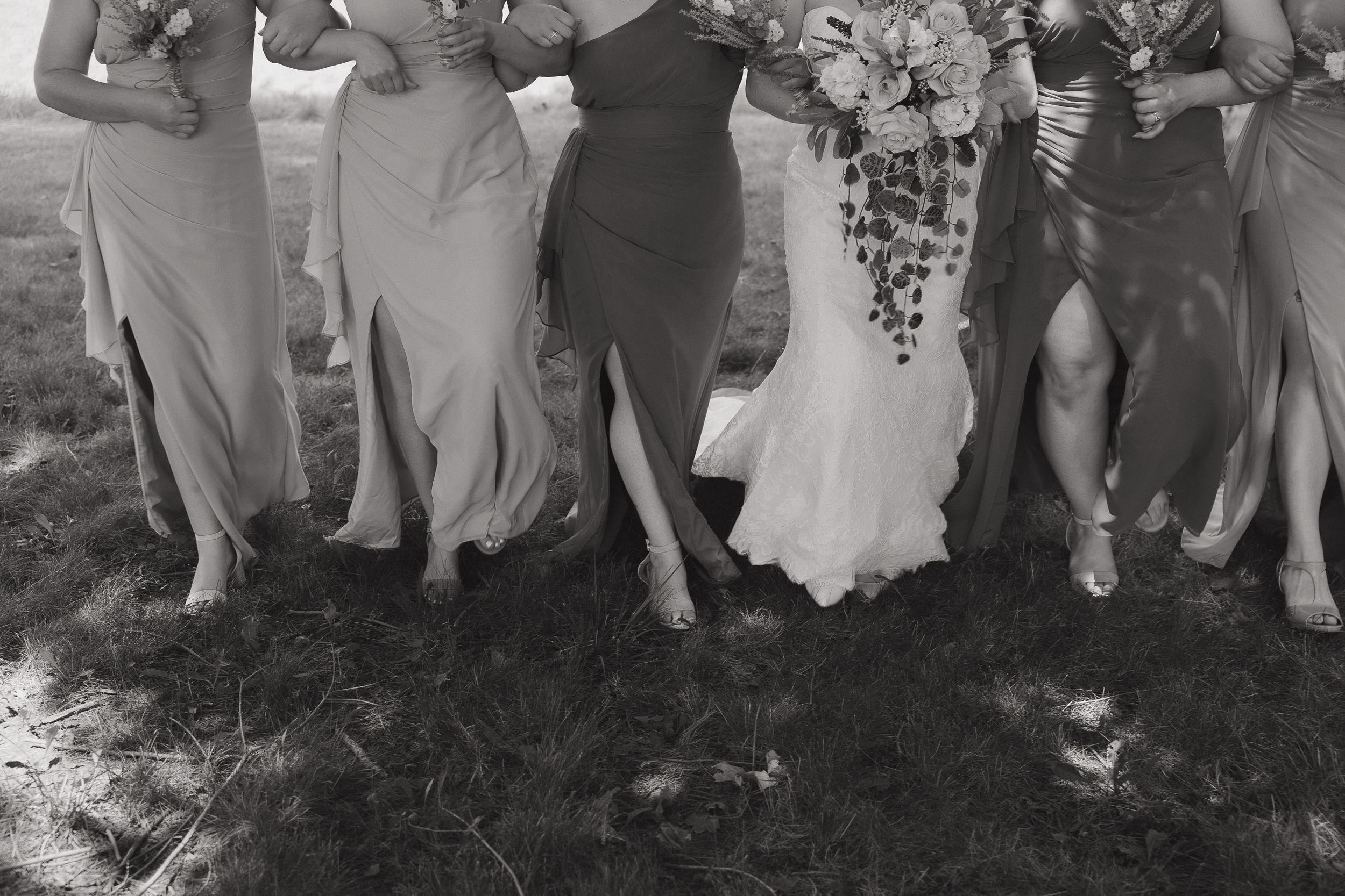 Black and white photo of wedding party showing off their shoes in a line.
