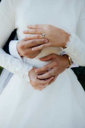 Close-up shots of hands with wedding rings and white dress details.