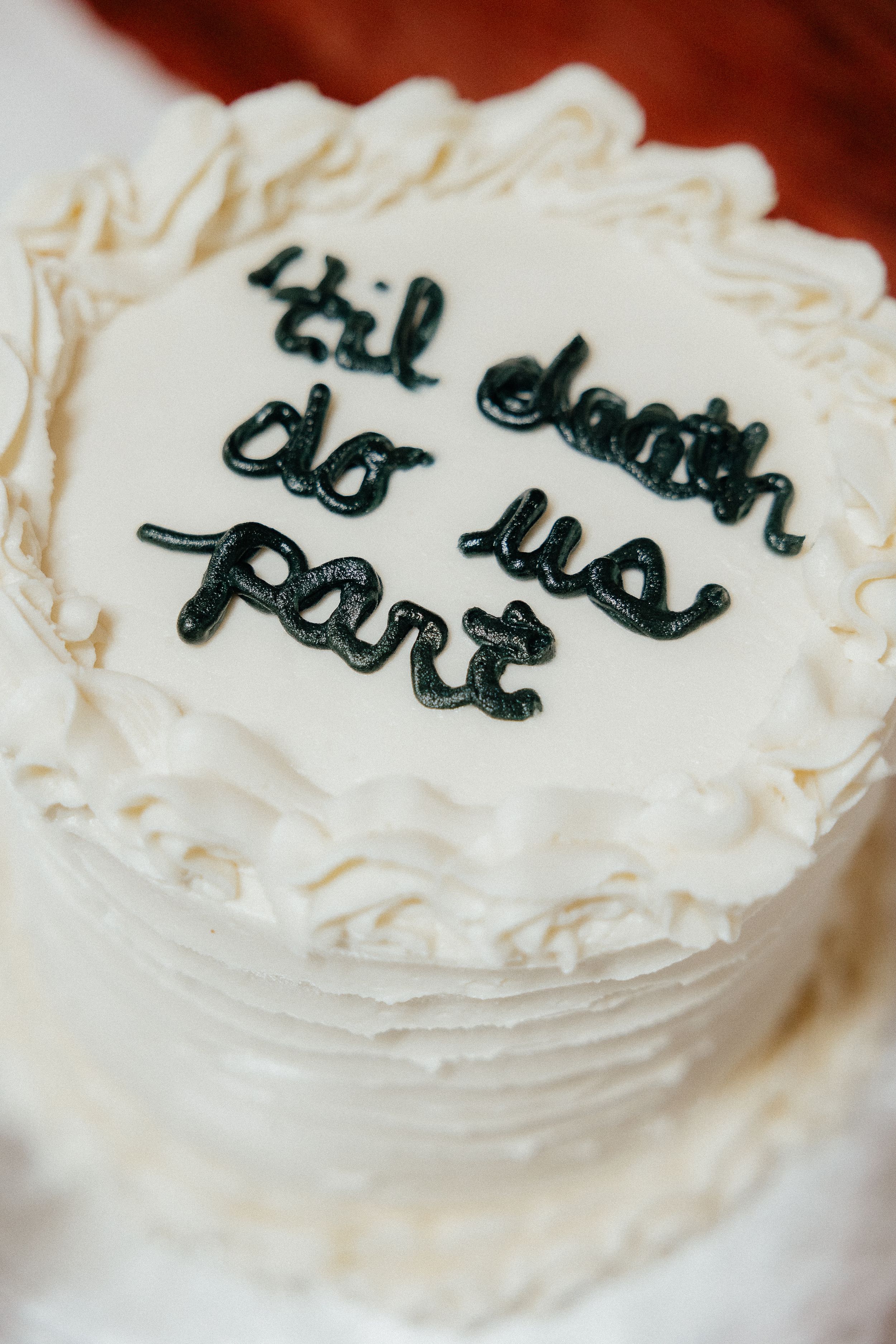 White frosted cake with black handwritten text on top.