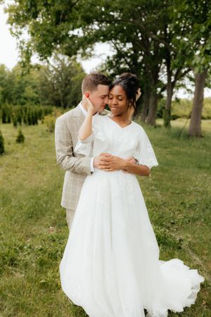 Intimate wedding portrait of couple embracing in natural outdoor setting.