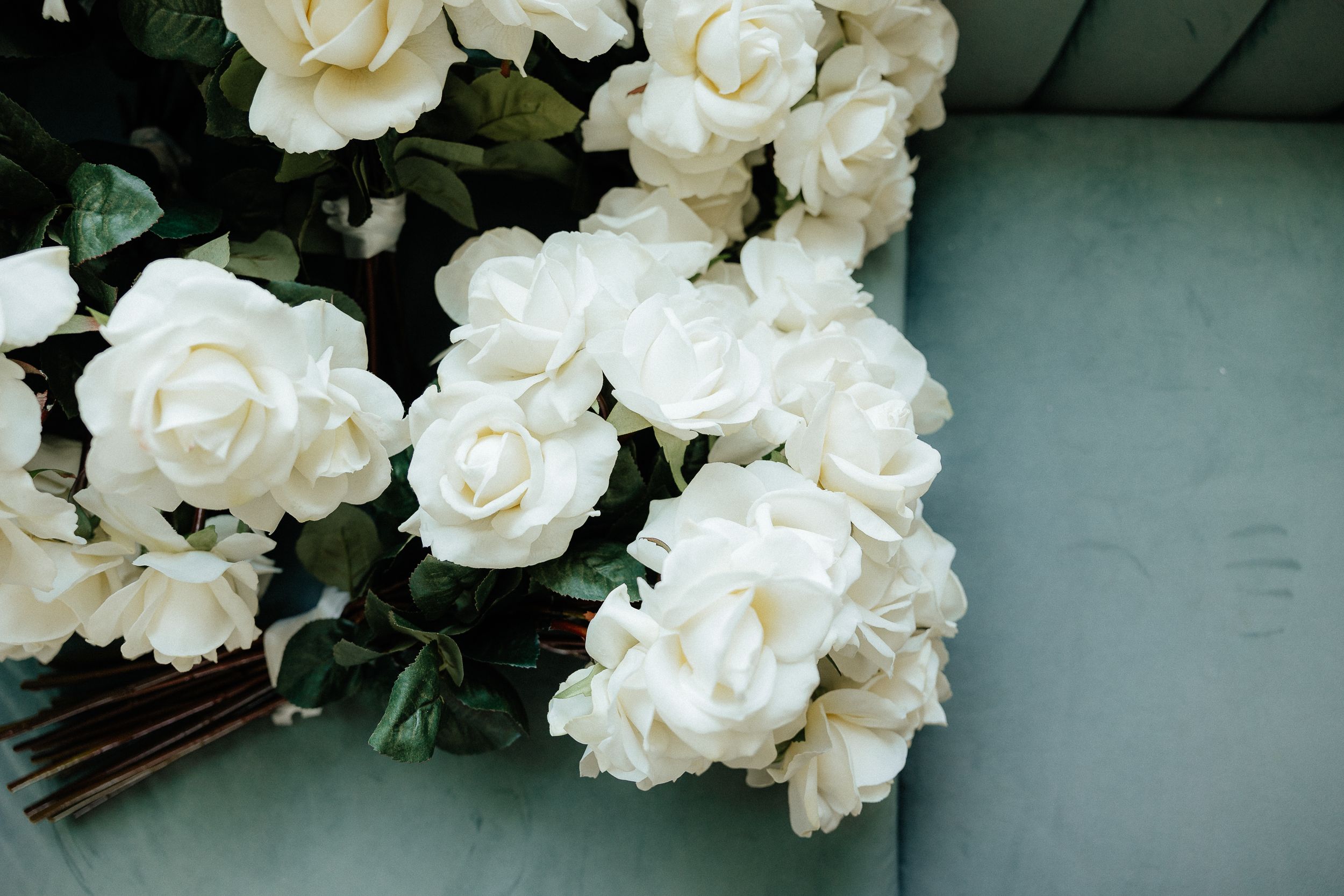 Elegant white roses with green foliage arranged against a muted background.