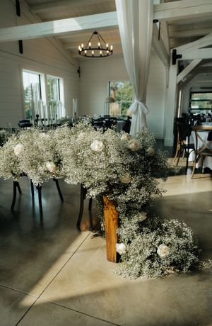 Baby's breath and white floral arrangement cascading down wooden table in modern venue.