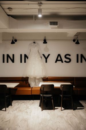 Wedding dress hanging on display in a minimalist room with text on the wall.