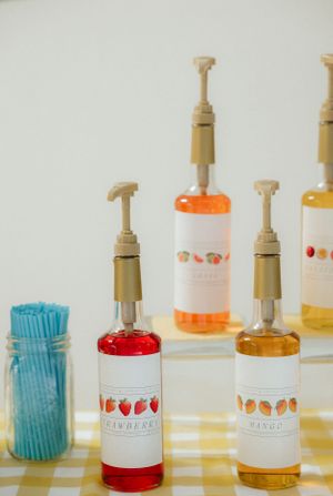 Collection of colorful soap dispensers with decorative labels arranged on a counter.