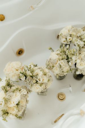 White roses and baby's breath floral arrangements in delicate glass vases.