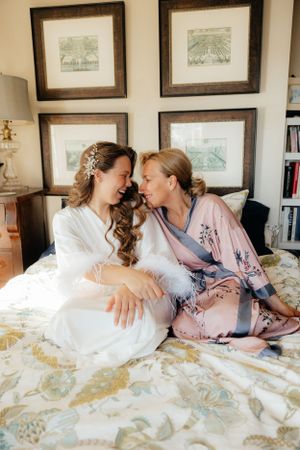 Tender moment shared on a bed with decorative pillows and framed artwork on wall.