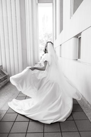 White wedding dress train flows across tiled floor in dramatic black and white photography.