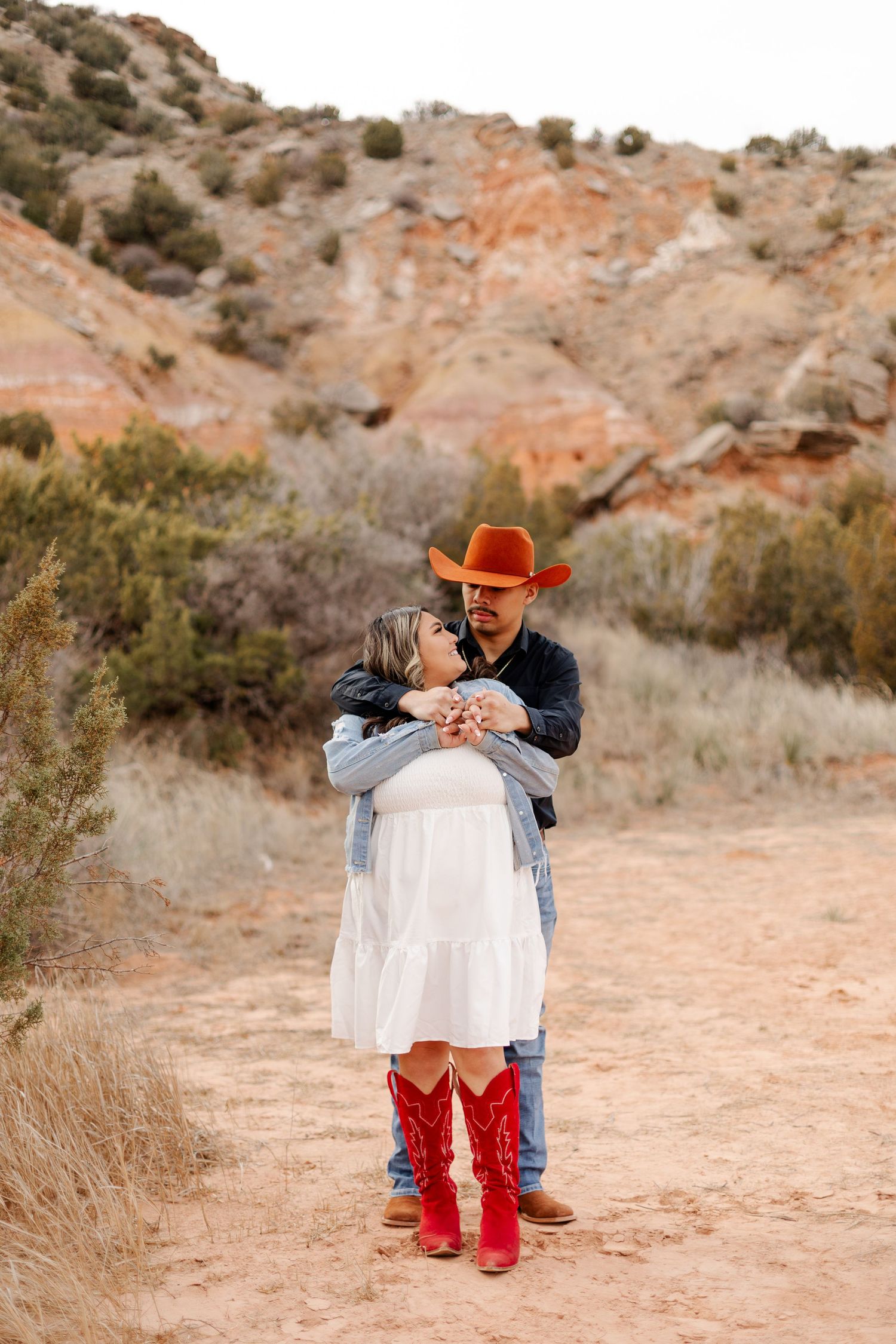 Romantic desert photoshoot with couple in western-inspired outfits.