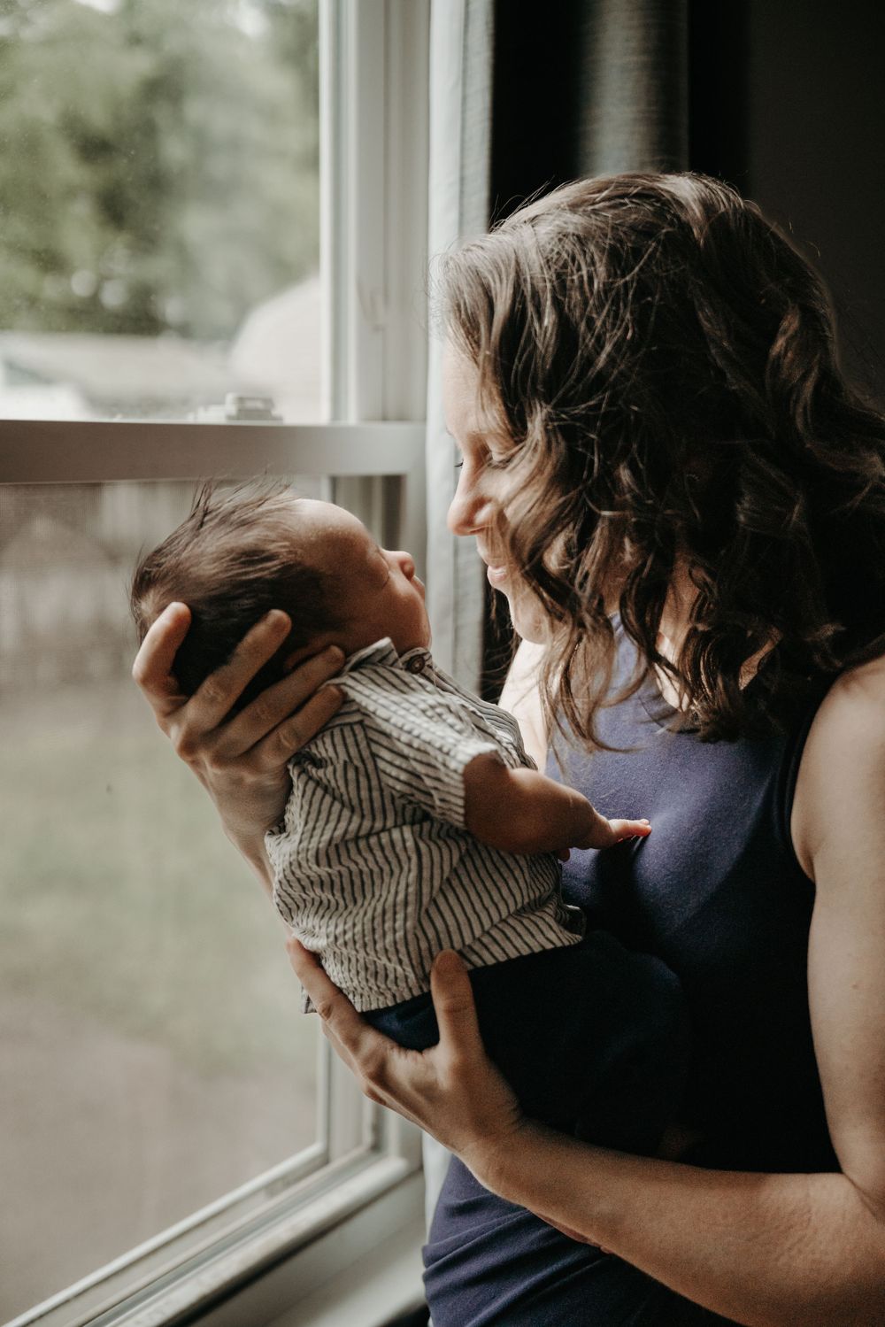 A tender moment between parent and infant by a window in natural light.