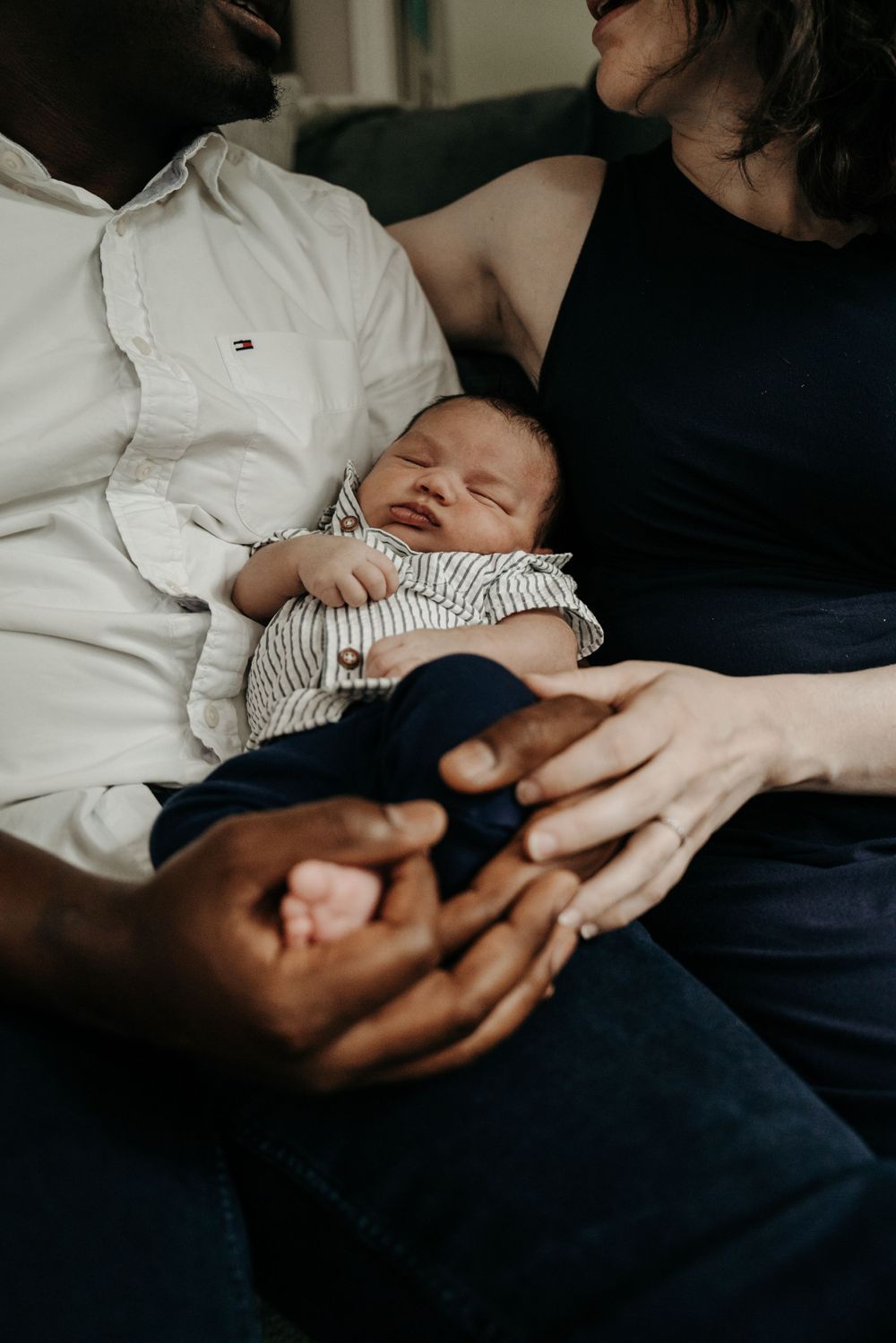 A family shares an intimate moment with their newborn baby on a cozy couch.