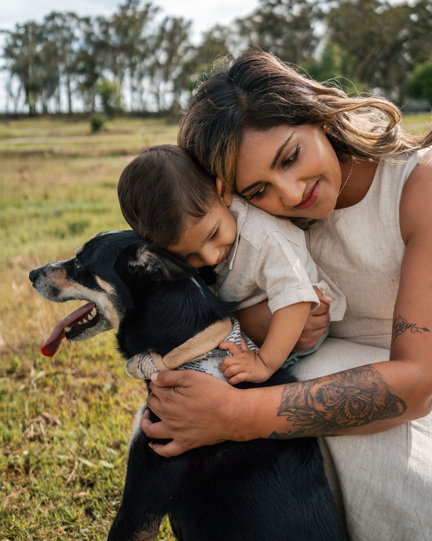 Mom hugging son while he is hugging his kelpi dog during a photoshoot in Sydney
