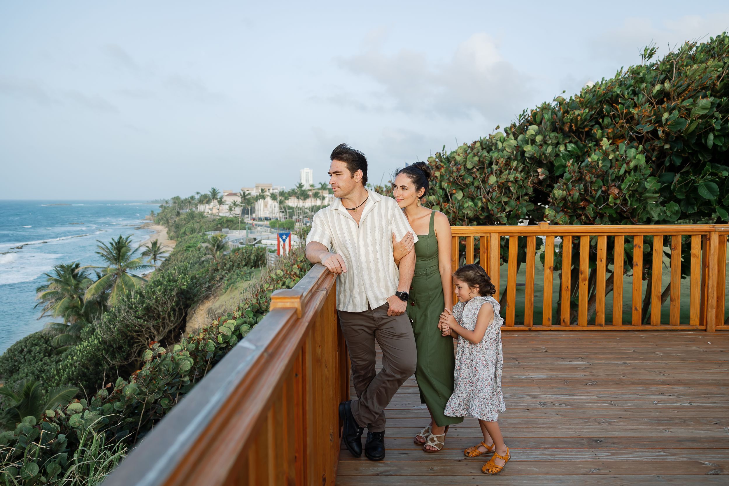 A family walking on a wooden boardwalk overlooking the ocean.