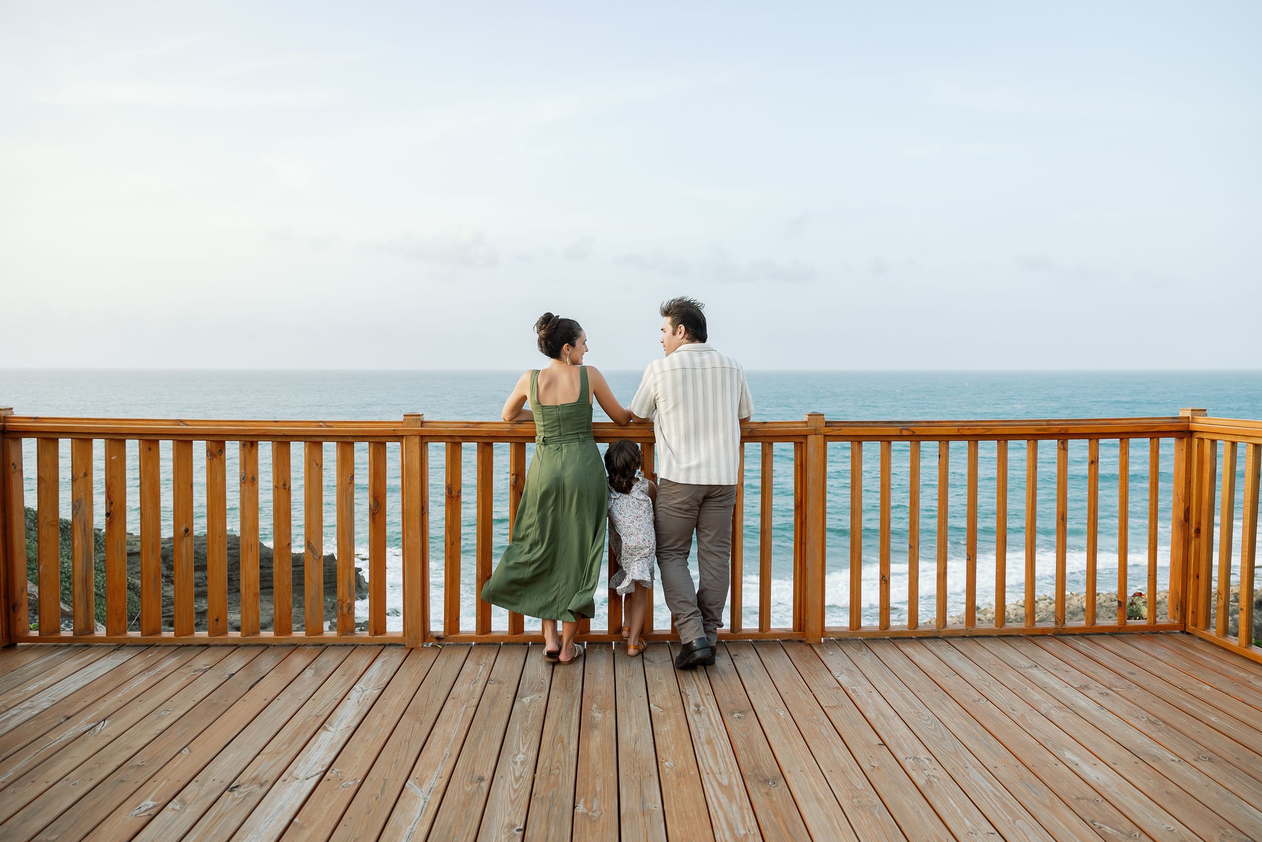 A couple stands on a wooden deck, enjoying the view of the surrounding area.