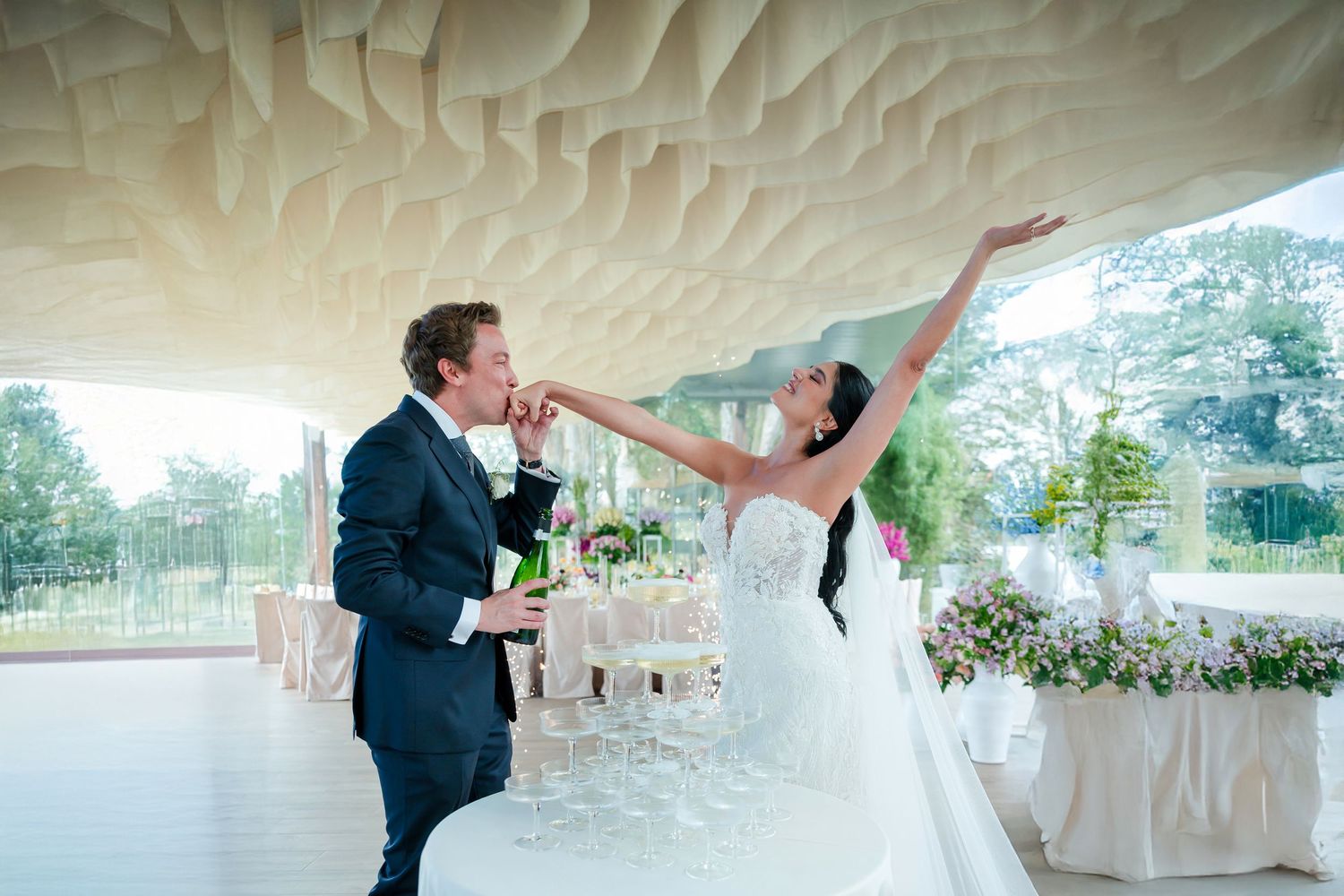 Elegant wedding couple dancing under a decorative white tent ceiling during their reception celebration.