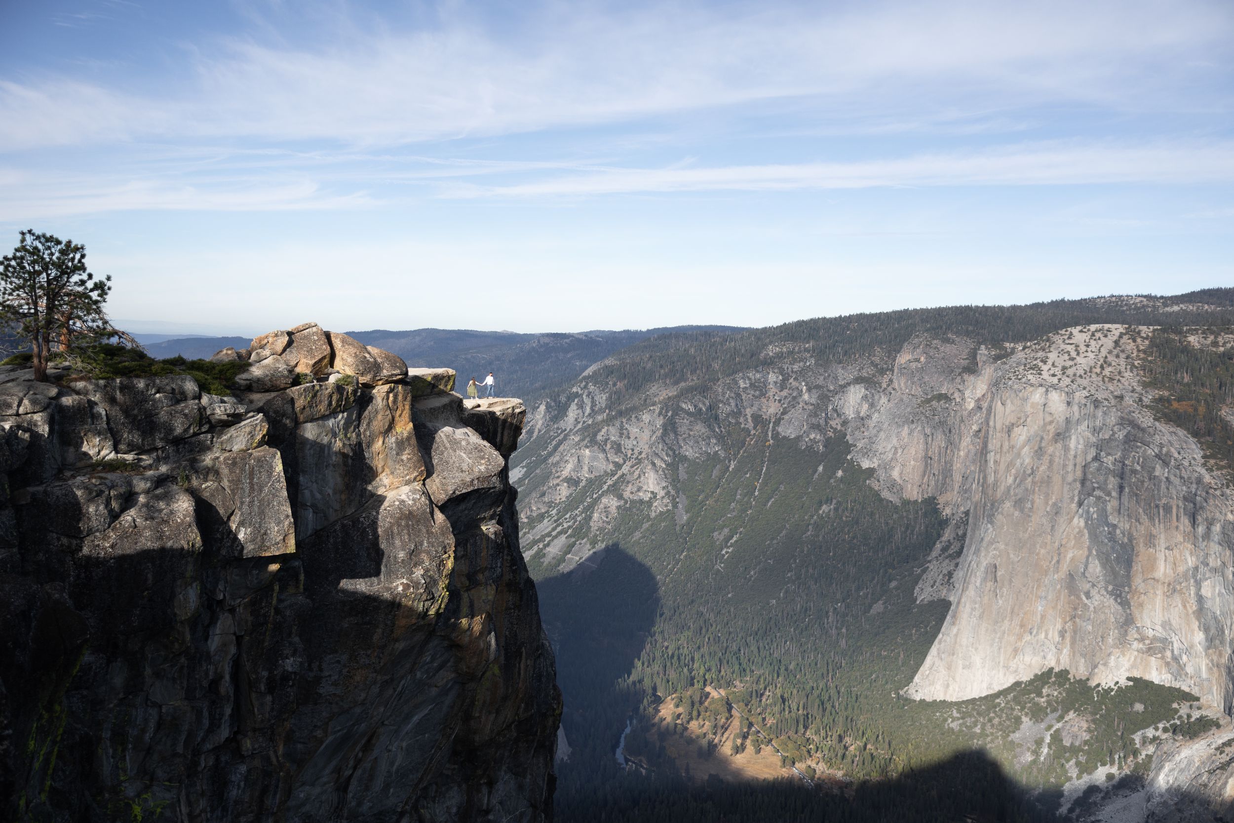 Dramatic landscape photo of Taft Point rocky overlook in Yosemite with El Capitan visible in the valley below.