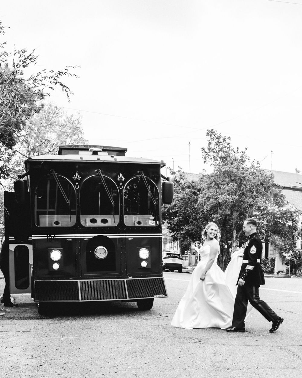 A classic black vintage trolley or party bus parked on a street in bright daylight.