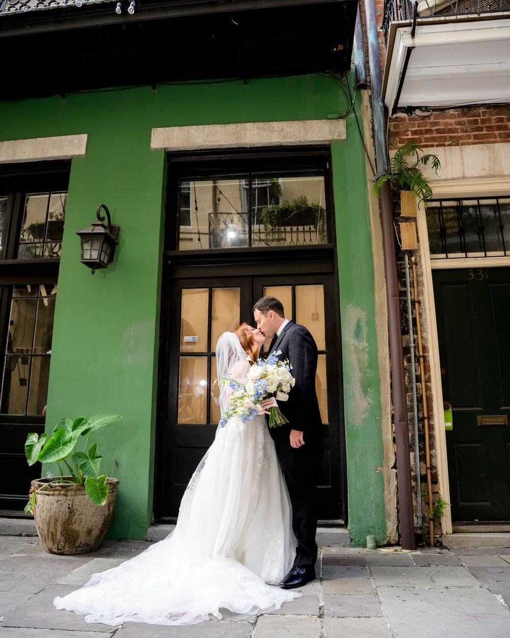 Wedding couple photographed at a rustic green storefront with vintage wooden accents and decorative elements.