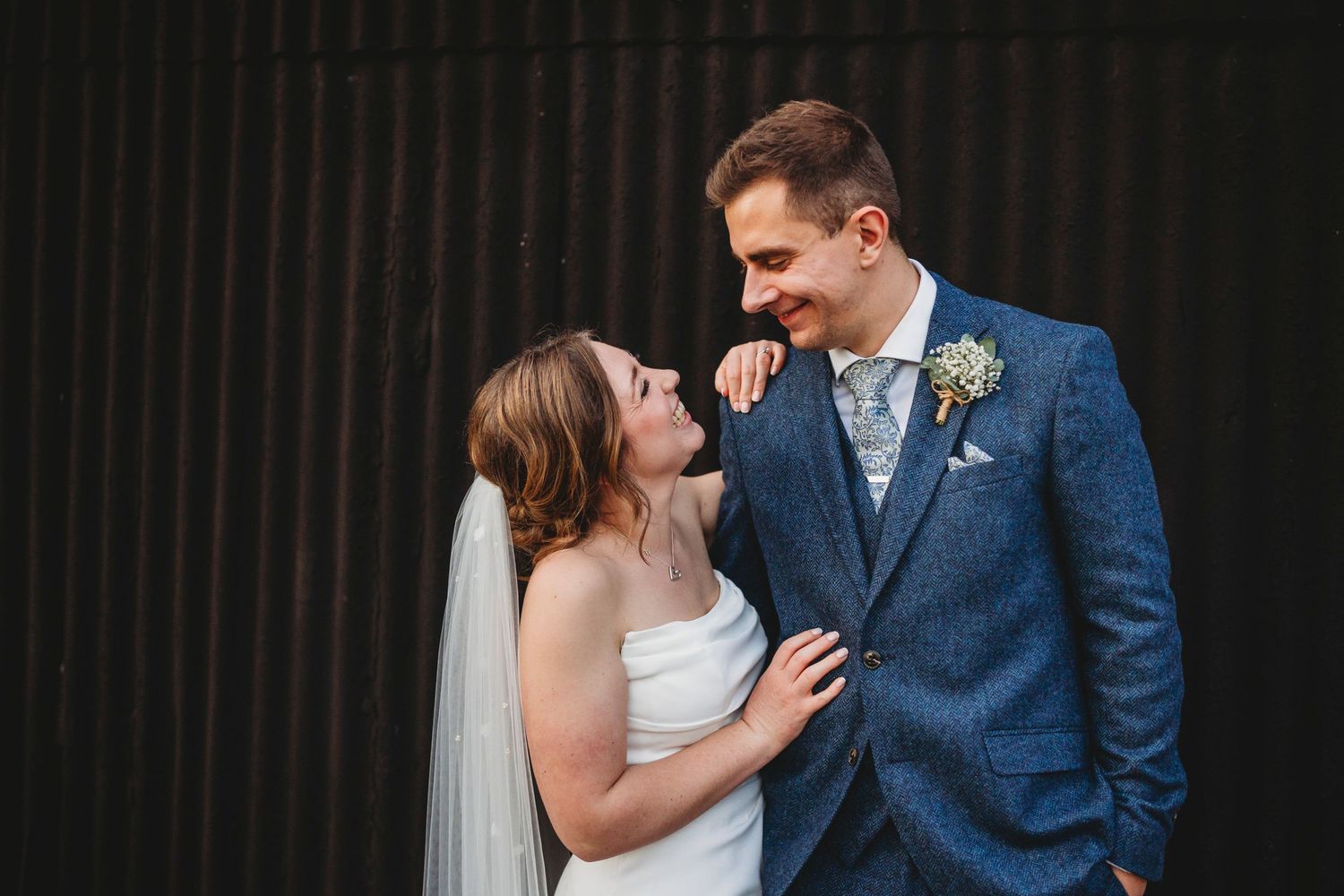 Romantic wedding couple portraits captured in dramatic black and white against a dark background.