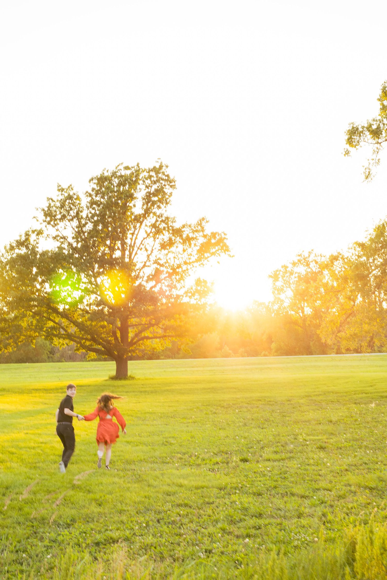 Two people running through sunlit field at golden hour.
