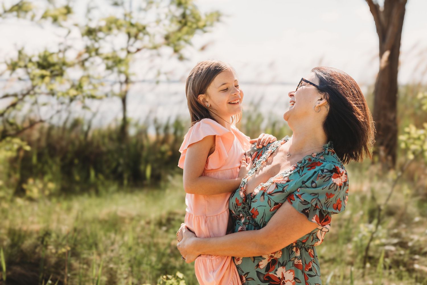 Candid loving moments captured between family members in a golden sunset field.