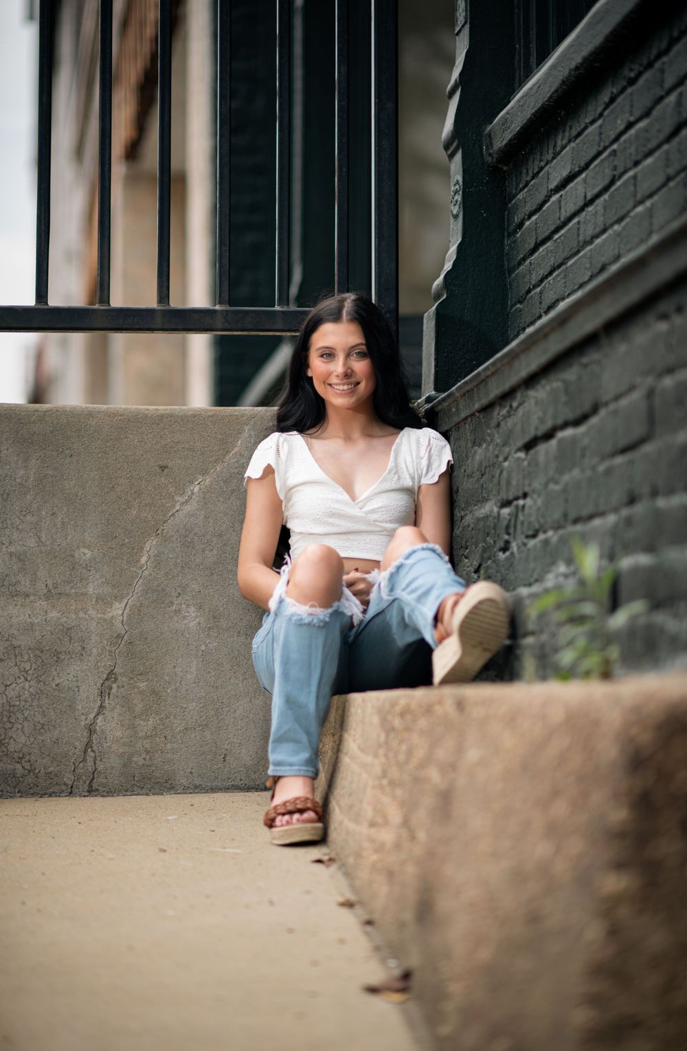 Girl sitting on street sidewalk