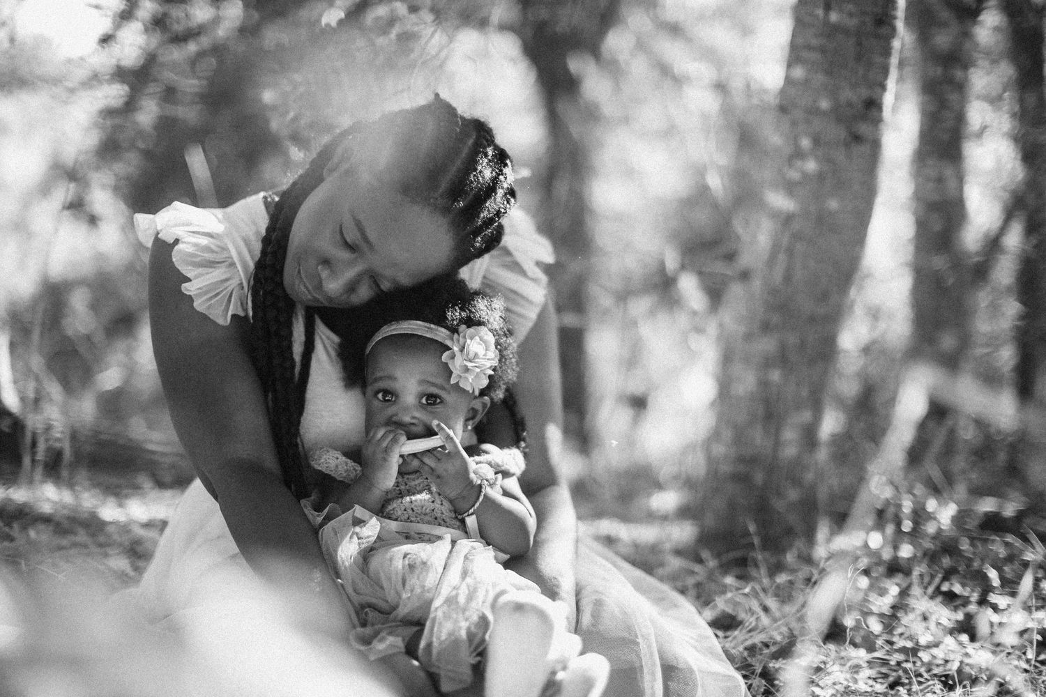 An intimate black and white moment captured between parent and child in a wooded setting.
