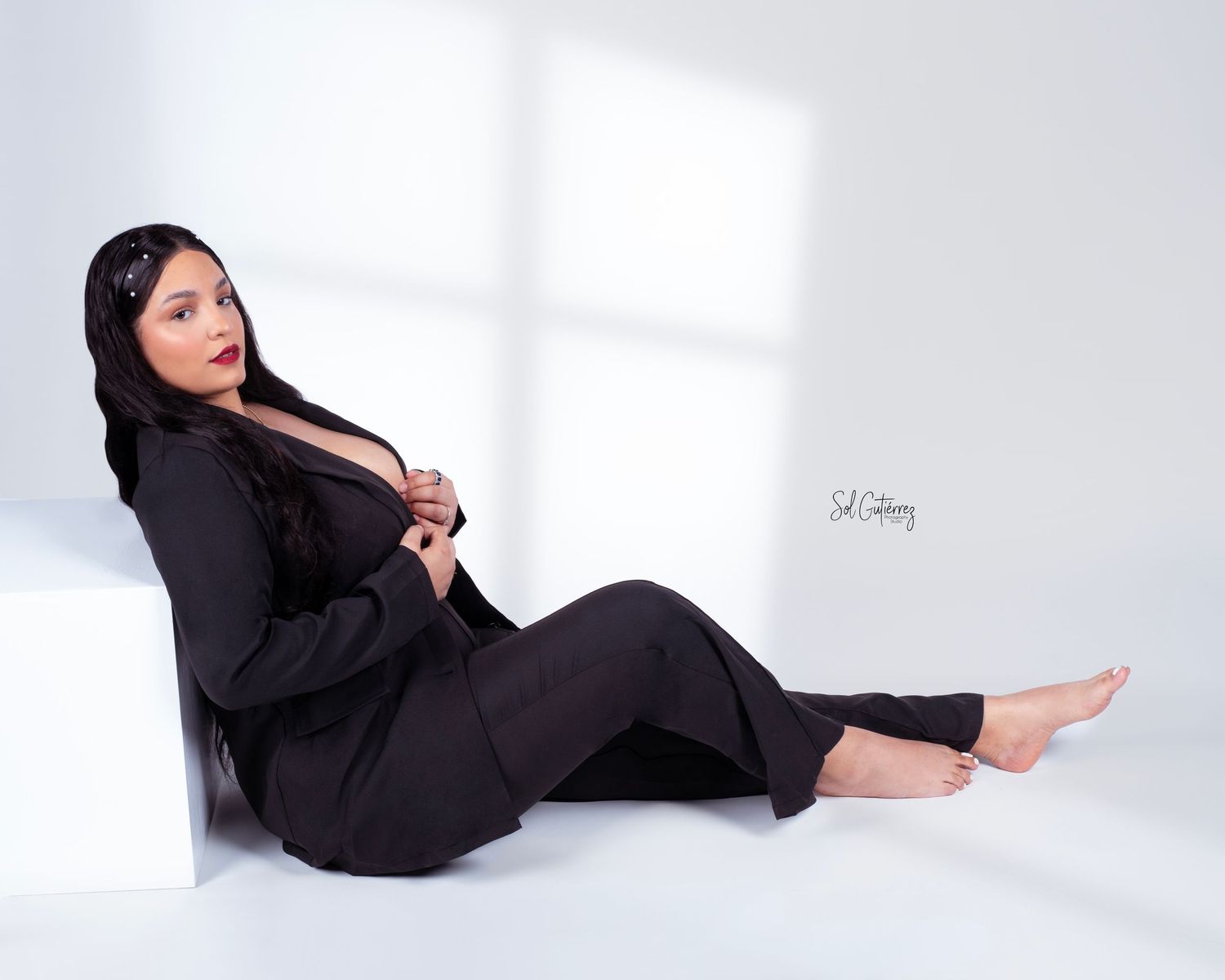 Studio portrait session in Allentown PA of woman in black suit posing on floor with soft natural window light