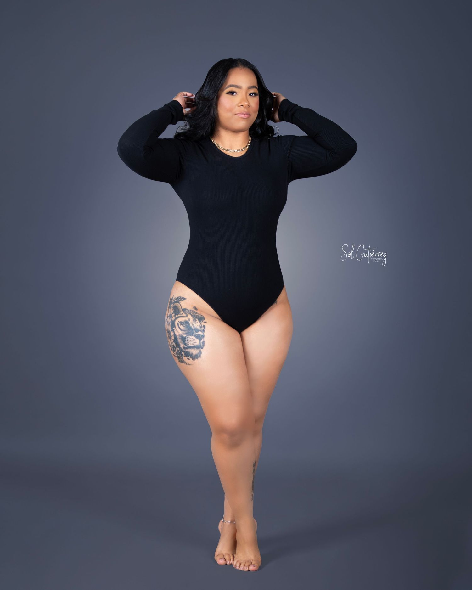 Full body studio portrait in Allentown PA of woman in black bodysuit posing confidently with tattoo.