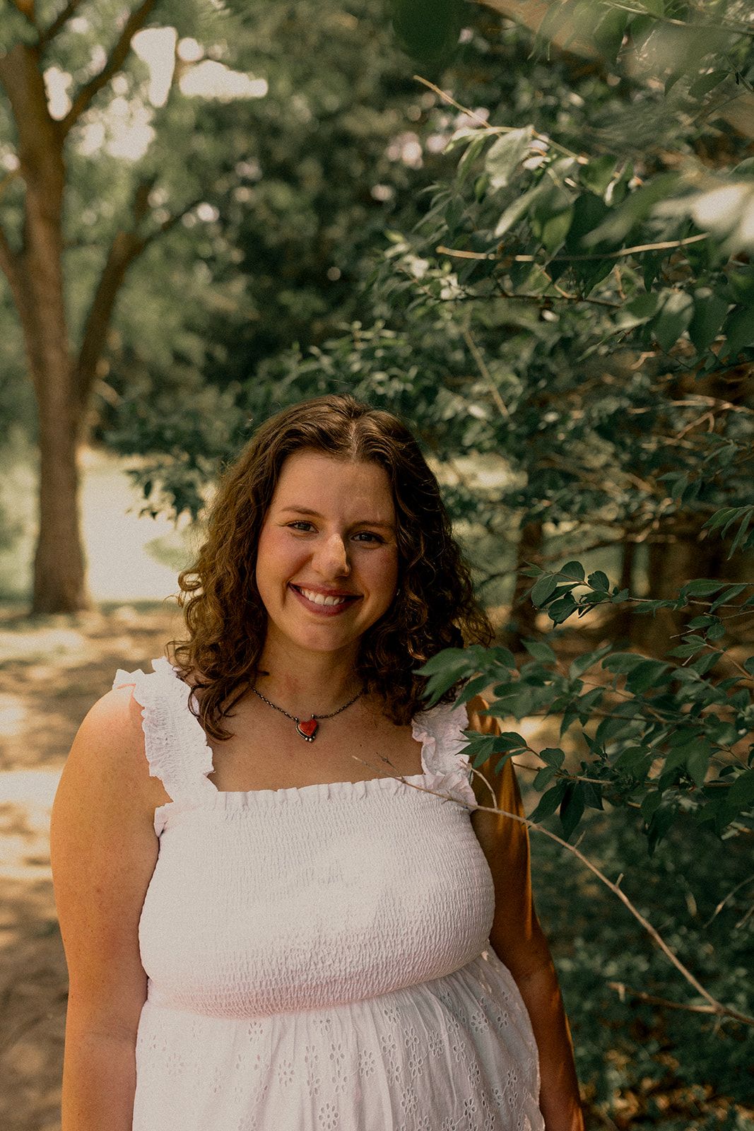 Candid portrait in dramatic lighting showing gentle smile and curled hair.