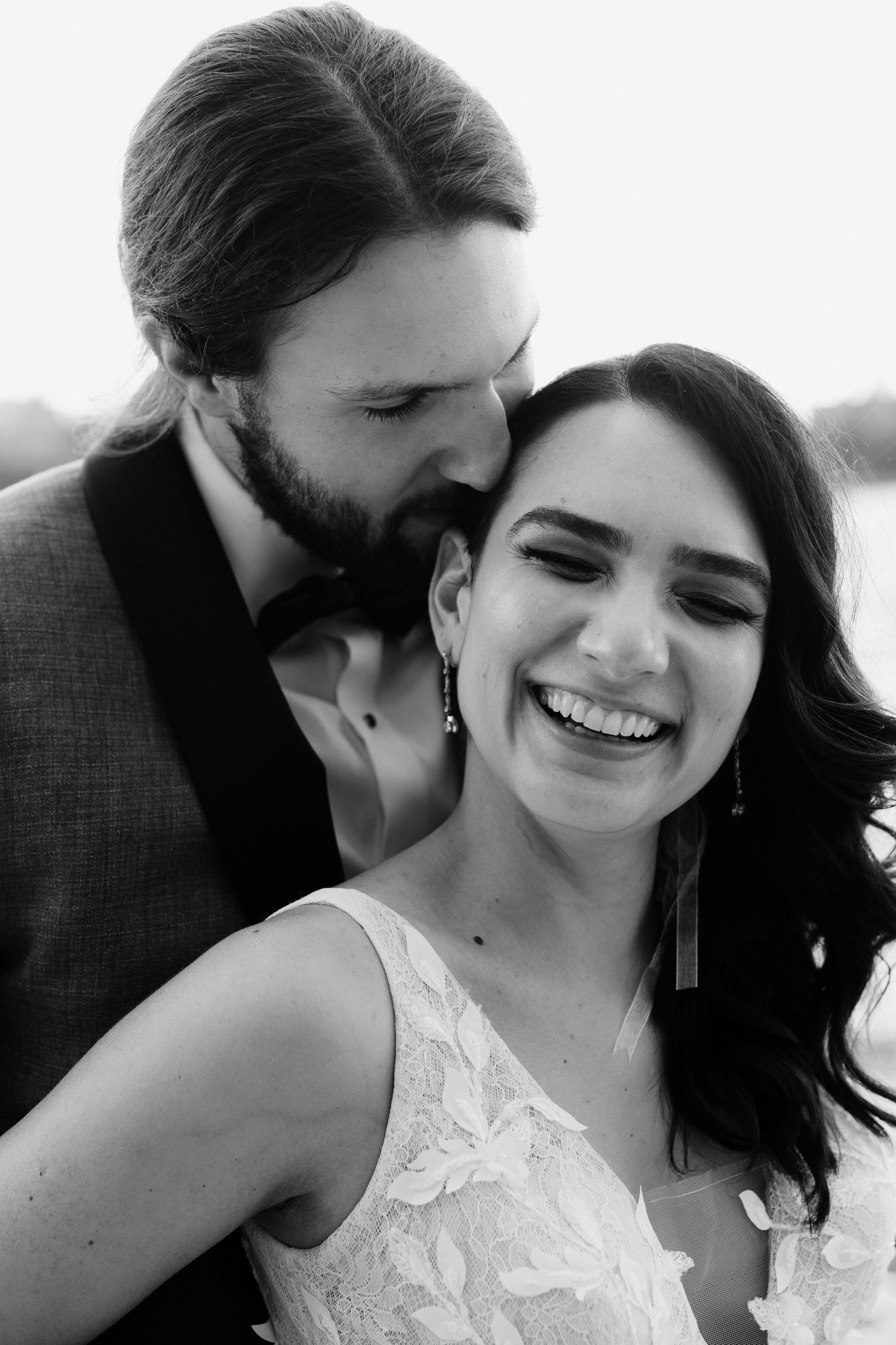 A romantic black and white wedding portrait showing a joyful candid moment between a couple.