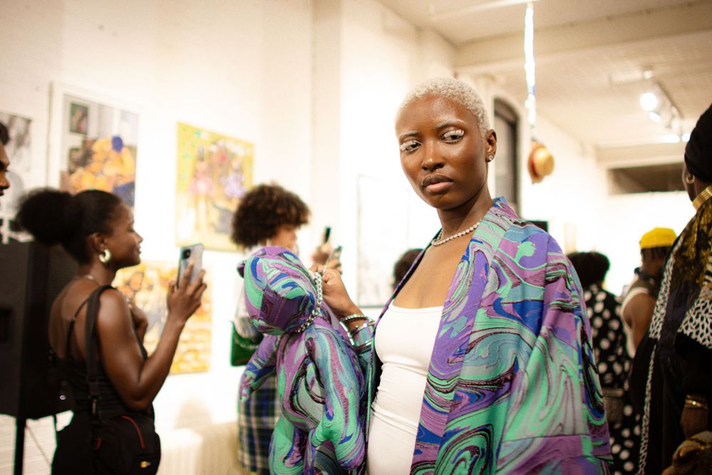 A sequence of photos shows a person wearing a colorful swirled backpack while interacting with art in a gallery.