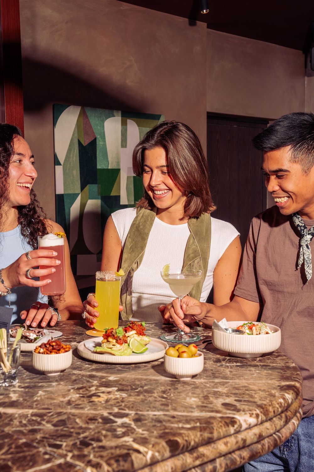 Friends enjoying a casual meal together at a restaurant with marble countertops while sharing laughs and conversation.