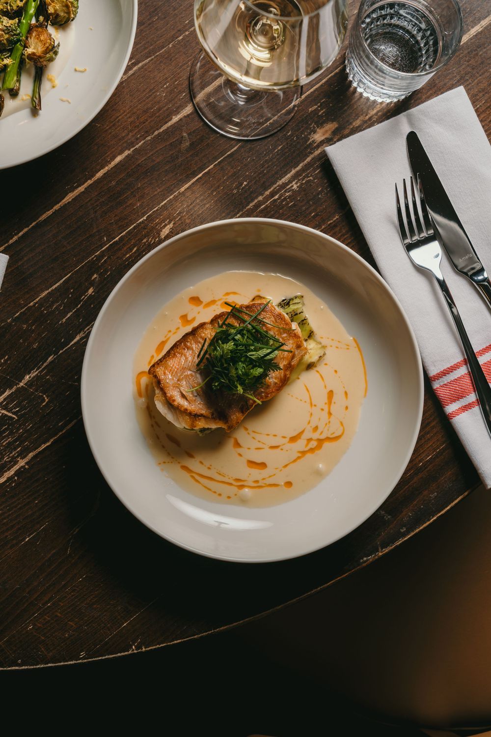 Sequence of plated dishes on a dark wooden table showing diminishing portions of food with decorative sauce drizzles.