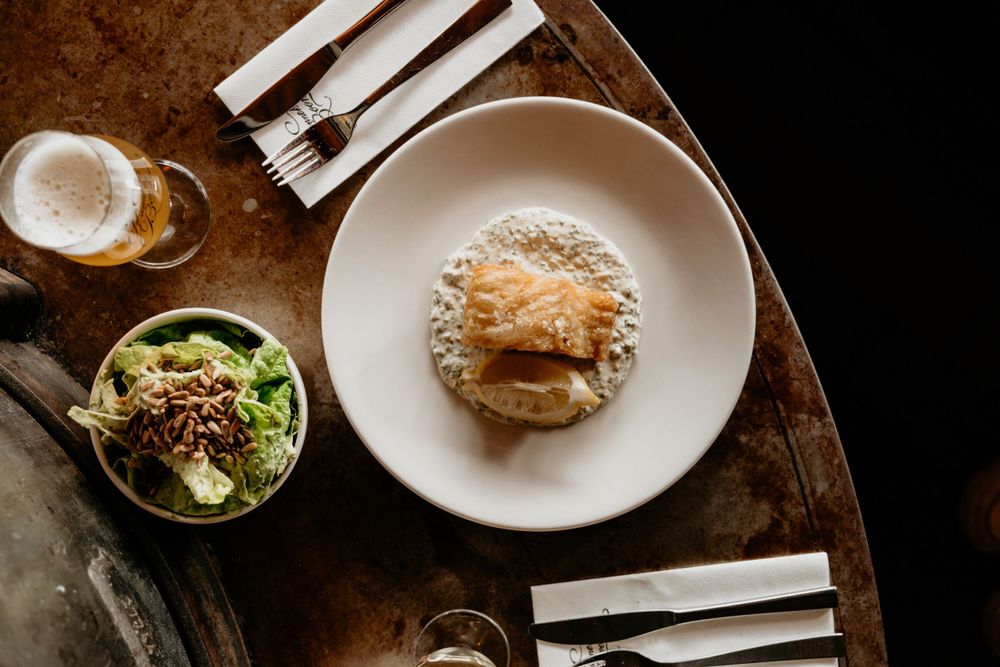 Burger with side salad on white plates viewed from above on wooden table.